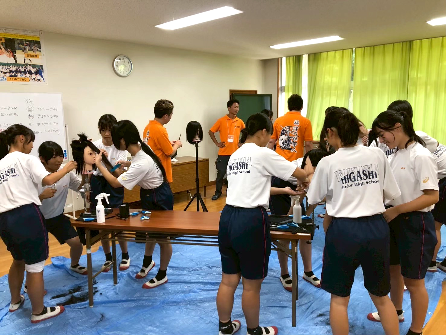 福津の仕事人の体験授業で美容師の青年部員が生徒たちに髪の切り方を教えている様子。
