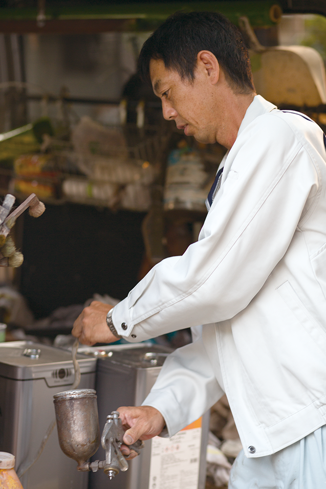 福津市の田中塗装代表の田中年明さんが作業している様子。